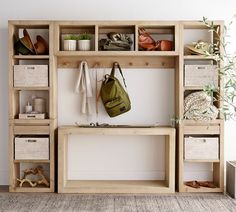 a wooden bench with baskets and bags on it in front of a wall mounted coat rack