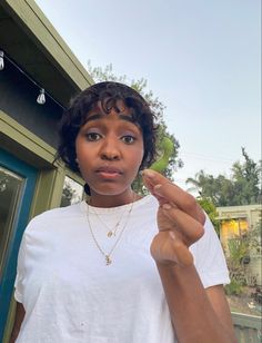 a woman holding a green bird in her right hand and pointing it at the camera