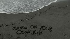 the writing you're on your own kid is written in the sand at the beach