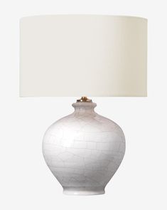 a white table lamp with a beige shade on it's base and an off - white drum light