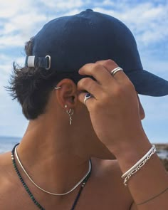 a man in a hat is looking at the ocean with his ear piercings on