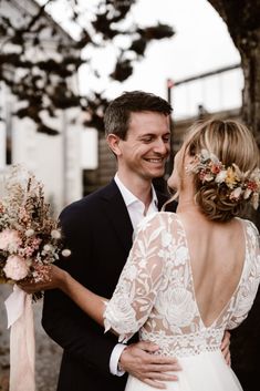 a bride and groom standing next to each other in front of a tree with flowers