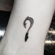 a black and white photo of a small umbrella tattoo on the ankle with an arrow