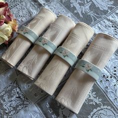 four folded napkins sitting on top of a lace doily next to a bouquet of flowers