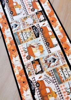 an orange and black quilted table runner on the floor with pumpkins around it