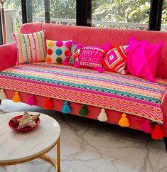 a pink couch with colorful pillows and tassels on it