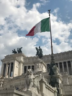 the italian flag is flying in front of an old building with statues on it's sides