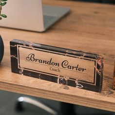 a wooden table topped with a vase filled with flowers and a personalized name plate