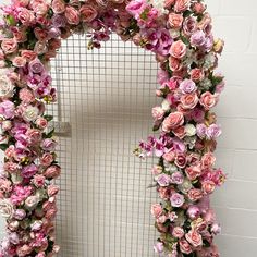 a white door covered in pink flowers next to a wall with a grid on it