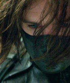 a close up of a person wearing a leather jacket and covering her face with a mask