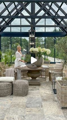 a woman standing next to a table in a room with lots of chairs and tables