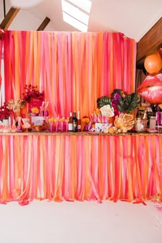 an orange and pink dessert table with balloons