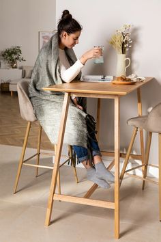 a woman sitting at a table with a cup of coffee