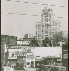 an old black and white photo of cars driving down the street in front of buildings