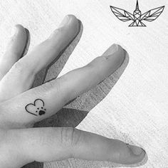 two fingers with small tattoos on them, one has a mouse and the other has a heart