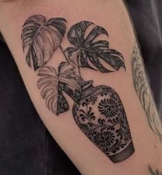 a tattoo with a vase and plants on it