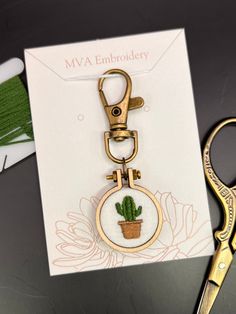 a pair of scissors sitting next to a card with a small cactus in the center