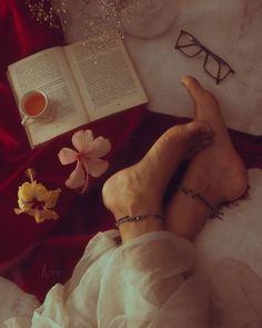 a woman laying on top of a bed next to an open book and flower pot