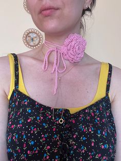 a woman wearing a pink crochet rose necklace