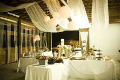 a table is set up with white linens and paper lanterns hanging from the ceiling