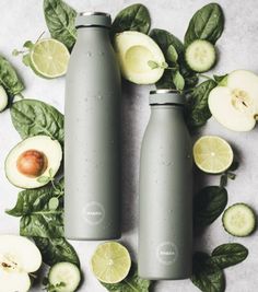 two gray water bottles surrounded by sliced cucumbers and leaves