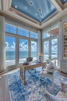 a living room filled with lots of furniture and large windows overlooking the ocean in front of it