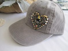 a baseball cap with a heart made out of buttons on it sitting on a table