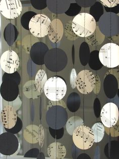 some musical notes are hanging from the glass curtain in front of a window that is decorated with black and white circles