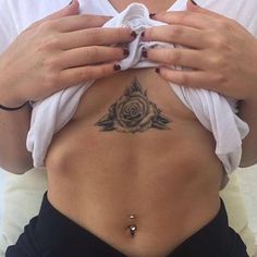 a woman with a rose tattoo on her back holding something in front of her stomach