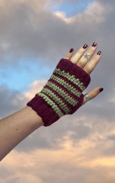 a woman's hand wearing a purple and green striped knitted fingerless glove