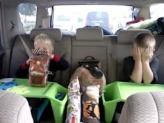 two young boys sitting in the back of a car with luggage on their laps and one boy holding his head