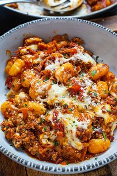 a bowl filled with pasta and meat covered in cheese