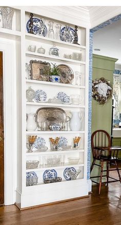 a white bookcase with blue and white china on it