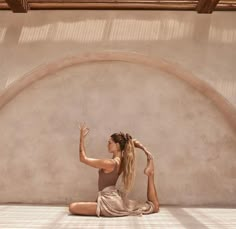 a woman is sitting on the floor with her hands up in the air while stretching