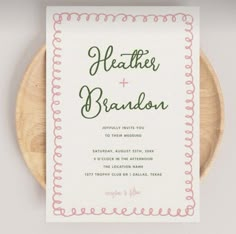 the wedding stationery is displayed on top of a wooden platter, which has a pink and green border