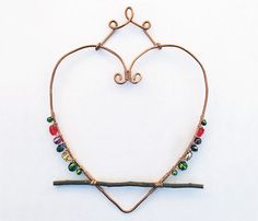 a heart shaped necklace with various colored beads hanging from it's side on a white surface