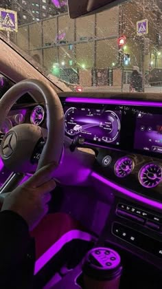 the interior of a car with purple lights and steering wheel controls in front of it