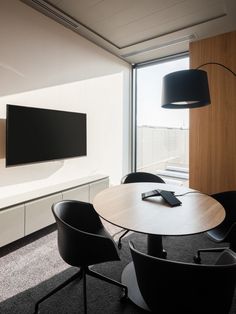 a table with chairs and a television mounted to the wall in an office setting,