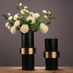 three black vases with white flowers in them