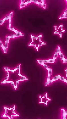 some pink and white stars on a black background with purple light in the dark,