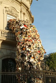 a giant bear made out of books on the side of a building next to a gate