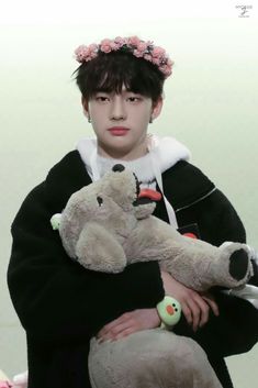 a young man holding two stuffed animals in his arms and wearing a flowered headband