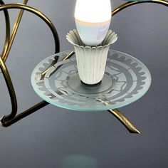 a glass plate with a candle on it sitting on a metal stand in the middle of a room