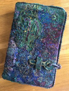 an altered book is sitting on a wooden table with beads and chains attached to it