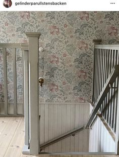 an open door leading to another room with floral wallpaper on the walls and wooden floors