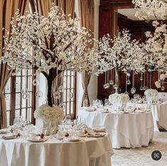 a dining room set up for a formal function with white flowers and centerpieces