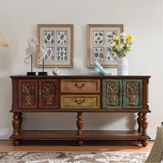 two framed pictures on the wall next to a wooden table with drawers and drawers in different colors