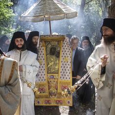 several men dressed in white and black robes holding an umbrella