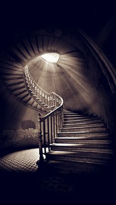 a spiral staircase with light coming from the top and below it in black and white