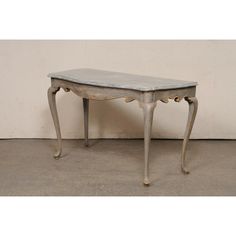 an old white table sitting on top of a cement floor